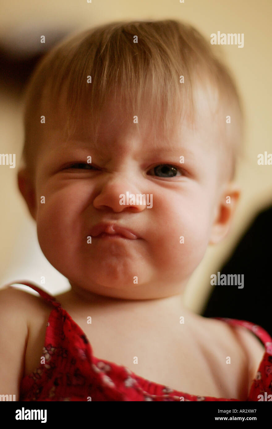 A toddler screws up her face in disgust at the camera. Stock Photo