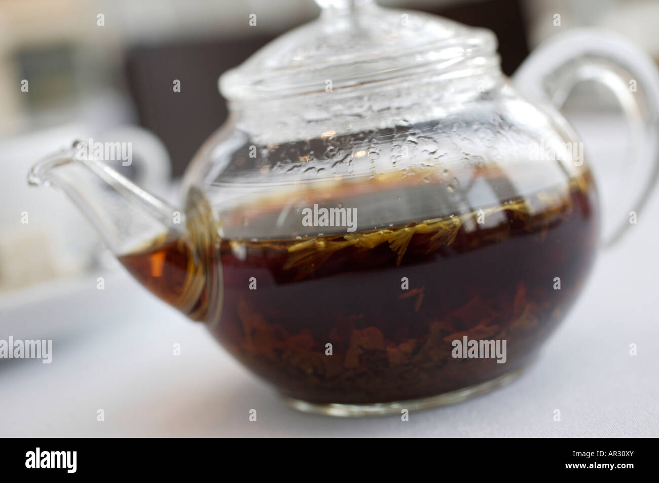 https://c8.alamy.com/comp/AR30XY/clear-glass-pot-of-loose-tea-on-a-white-table-cloth-AR30XY.jpg