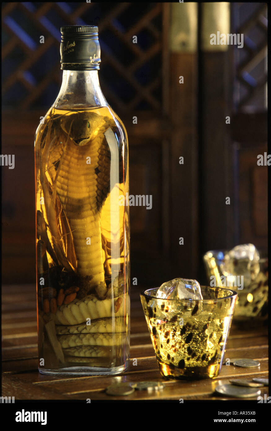 Bottle of spirits with pickled cobra and glass with ice cubes, Saigon, Vietnam, Asia Stock Photo
