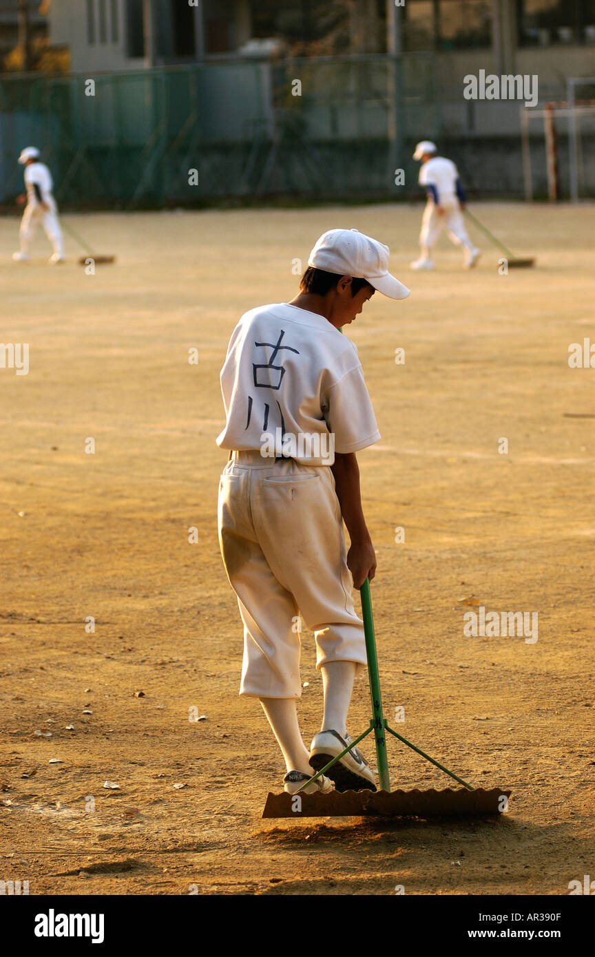 Japanese little league baseball players rake the ground after a game in school in Kyoto Japan Stock Photo