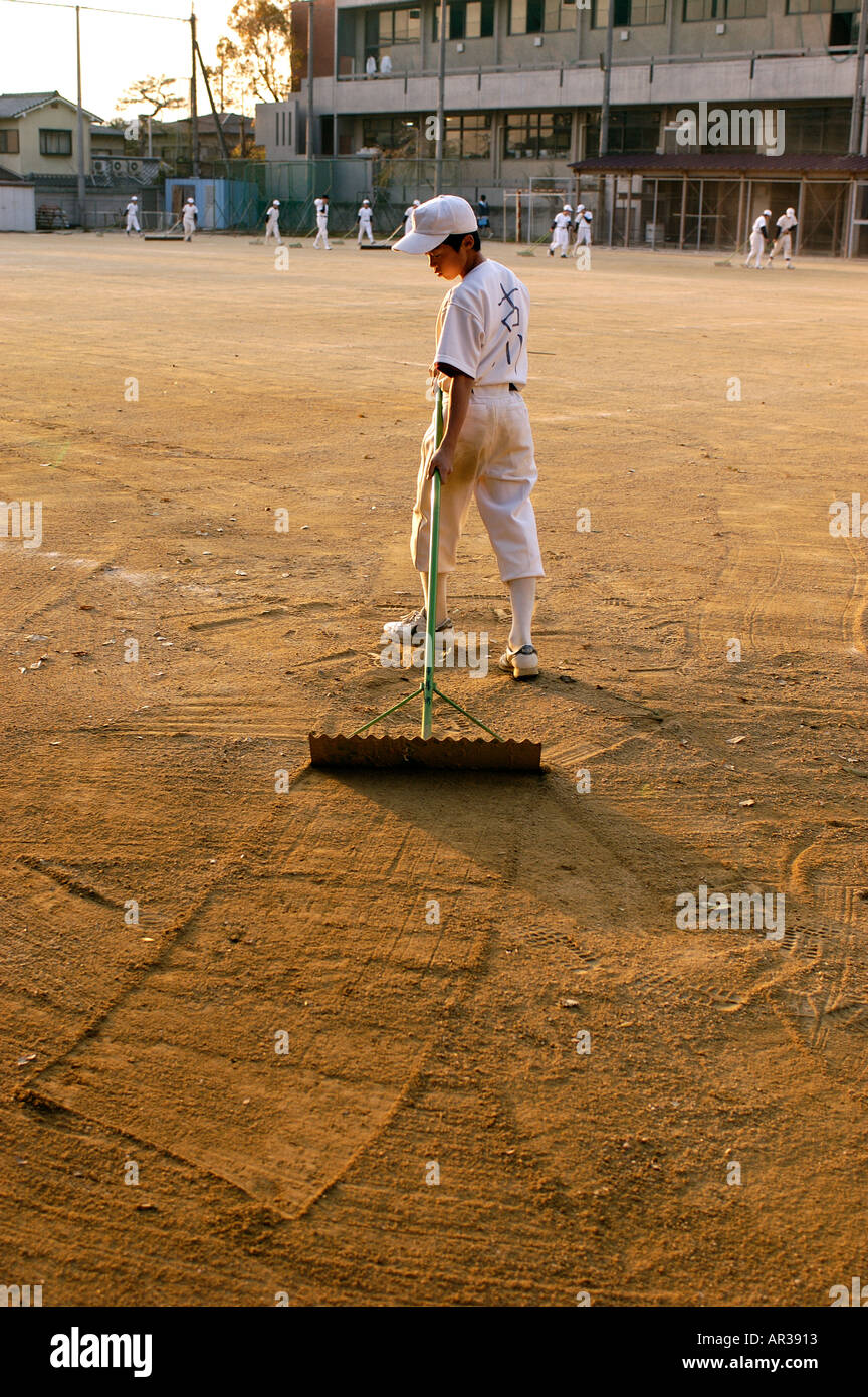 Japanese little league baseball players rake the ground after a game in