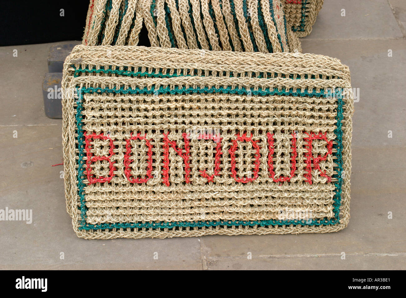 Traditional doormats at market with the word BONJOUR picked out in red Stock Photo