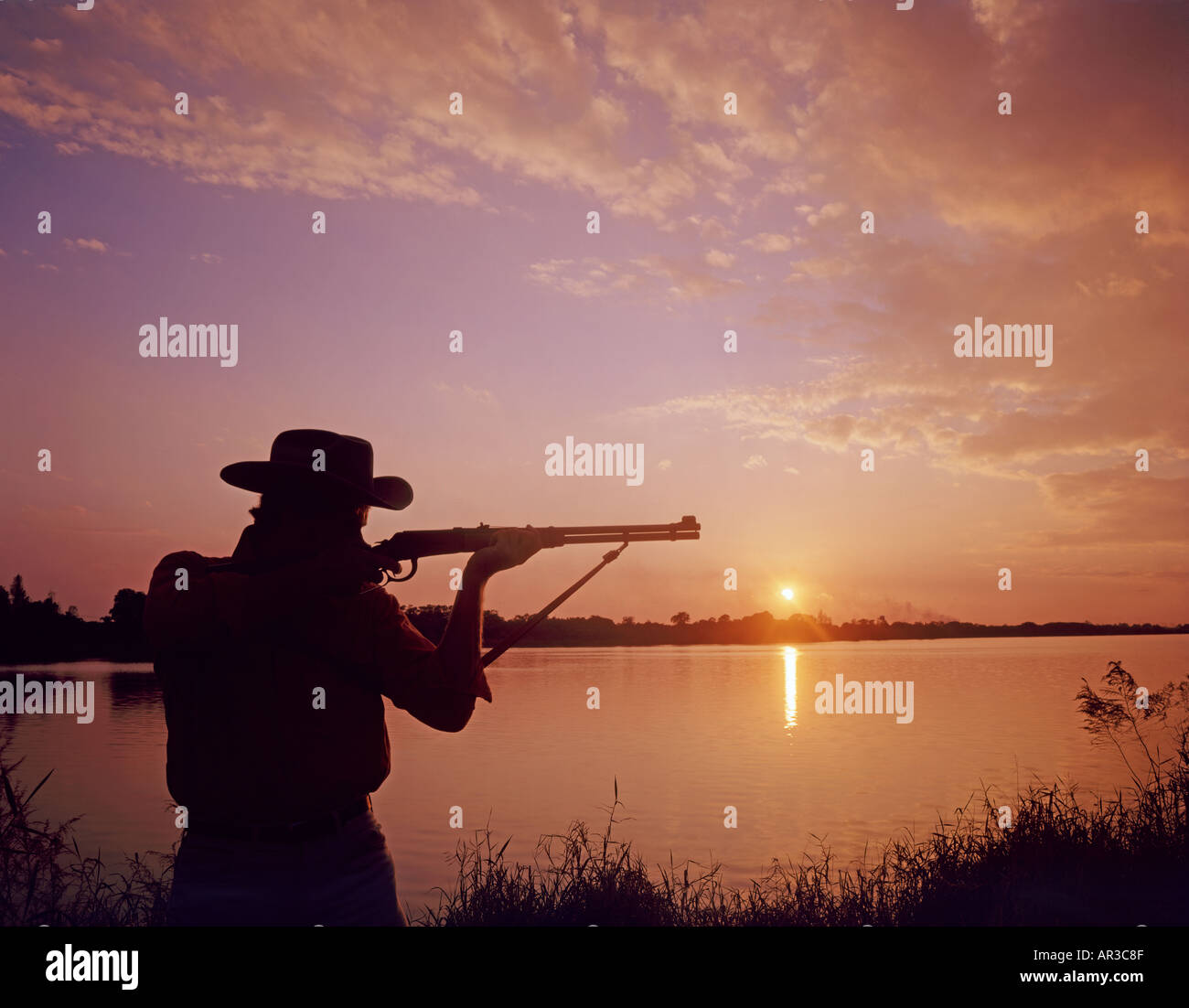 hunter taking aim at waterfowl at sunset on Florida lake Stock Photo