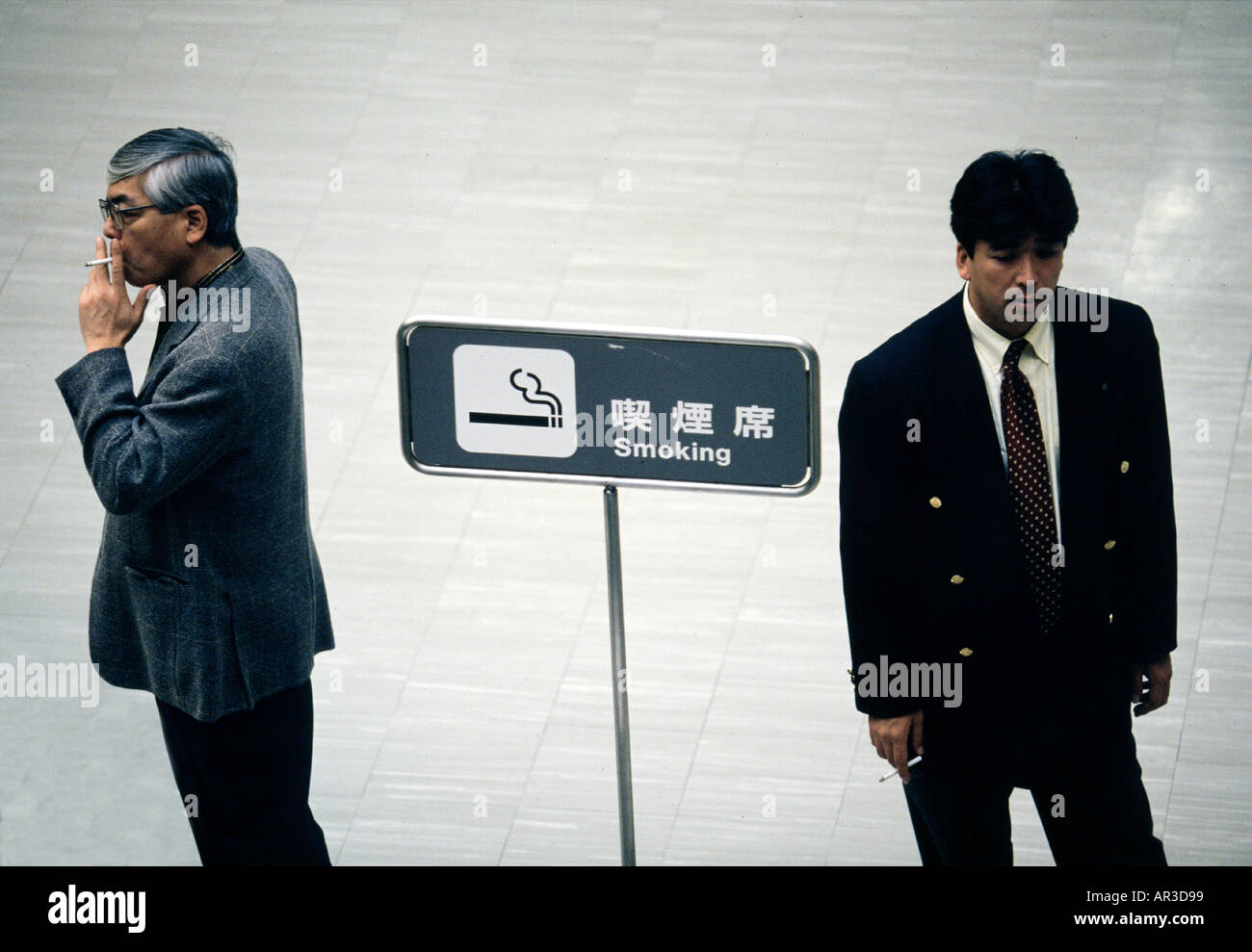A pair of men smoke in the smoking lounge of Narita Airport in Tokyo Japan Stock Photo