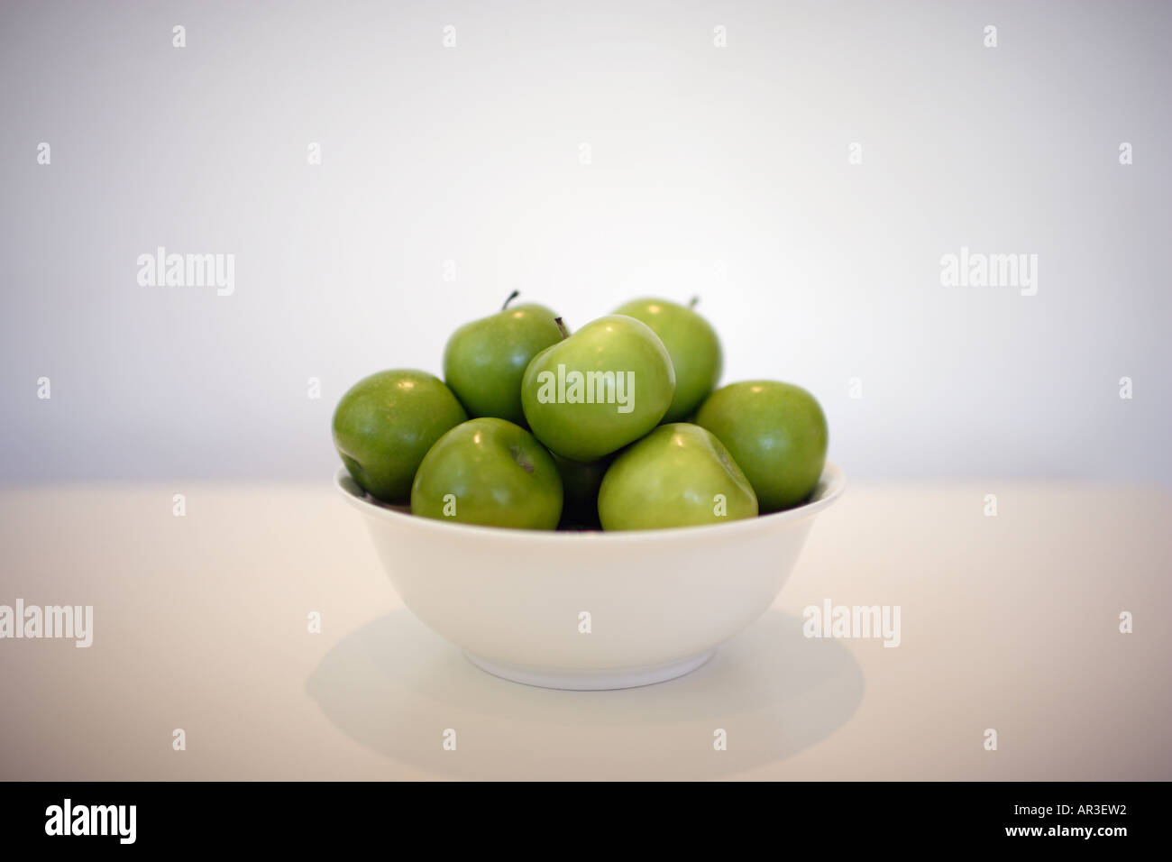 Bowl full of green apples on a white table Stock Photo