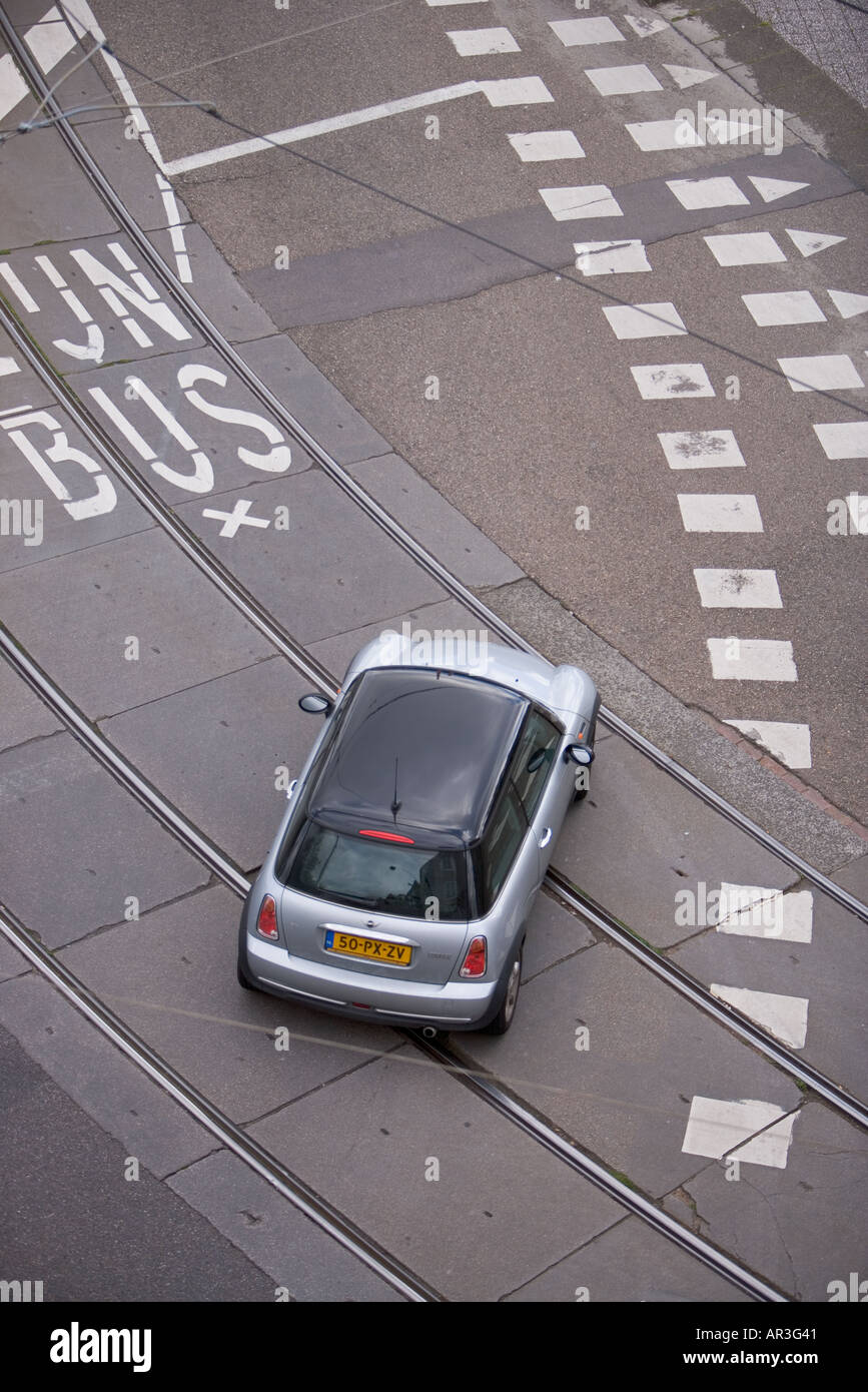 HOLLAND AMSTERDAM OVERHEAD VIEW OF SILVER AND BLACK MINI COOPER DRIVING ACROSS TRAM RAILS LINES AND BUS LANE Stock Photo
