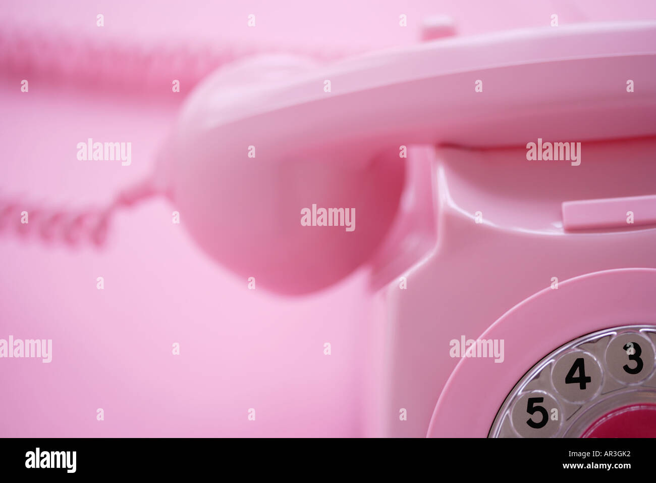 Detail of a pink telephone receiver on pink background Stock Photo