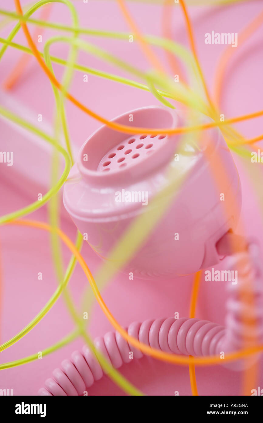 Pink telephone receiver with multi coloured wires on pink background Stock Photo