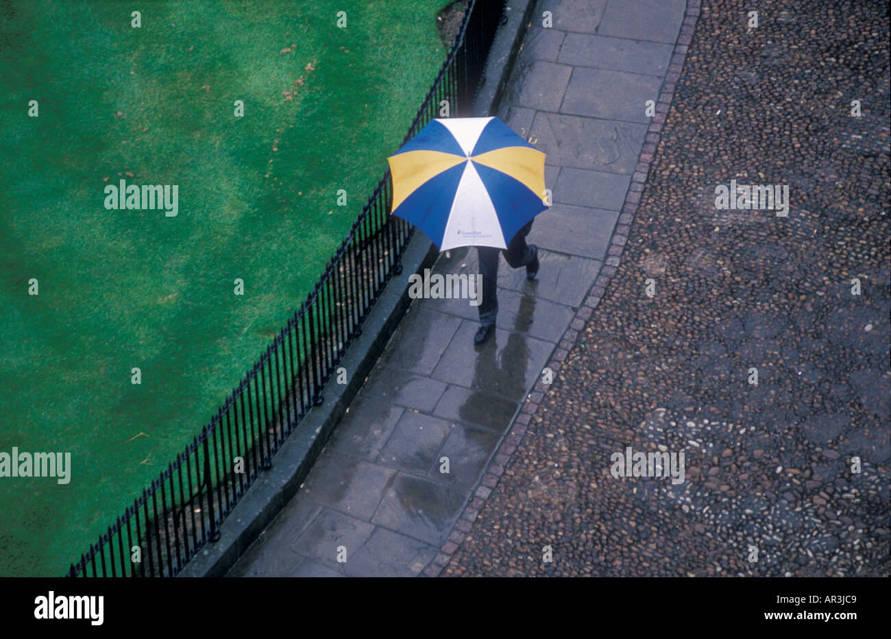 Man walking in rain with umbrella. Stock Photo