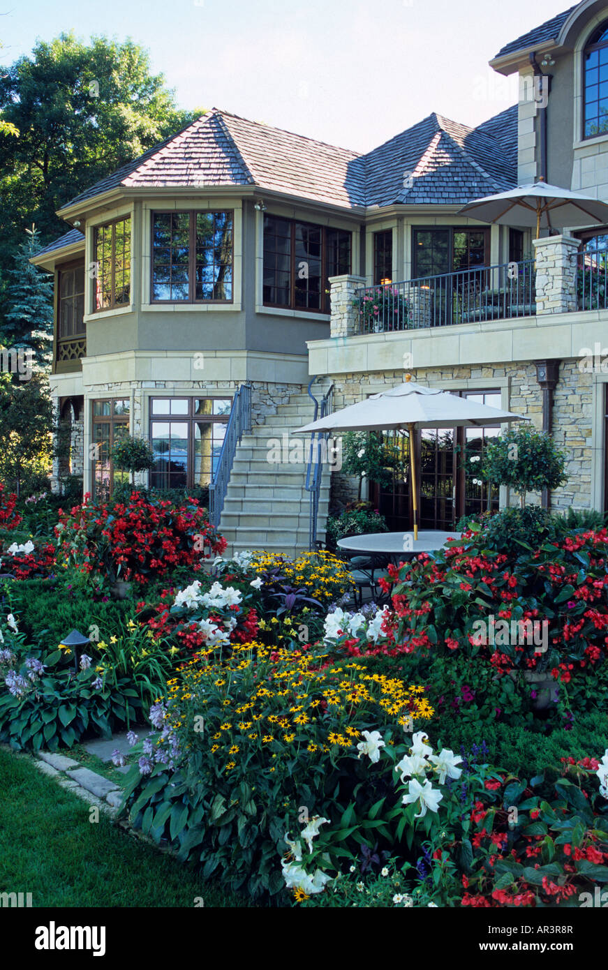 BACK VIEW OF LUXURY MINNESOTA HOME WITH PATIO AND BORDER GARDEN OF