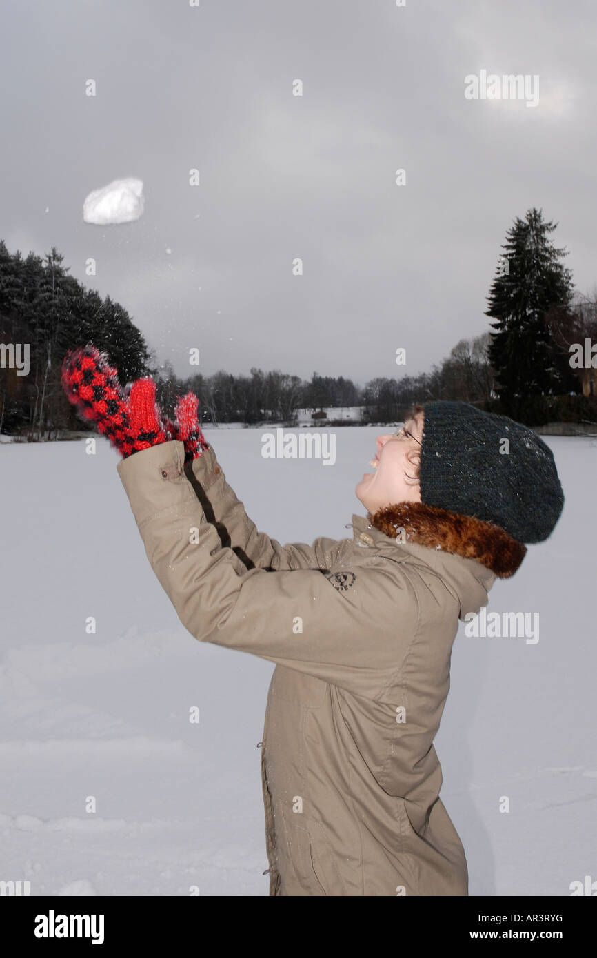 Woman throwing snowball into the air Stock Photo