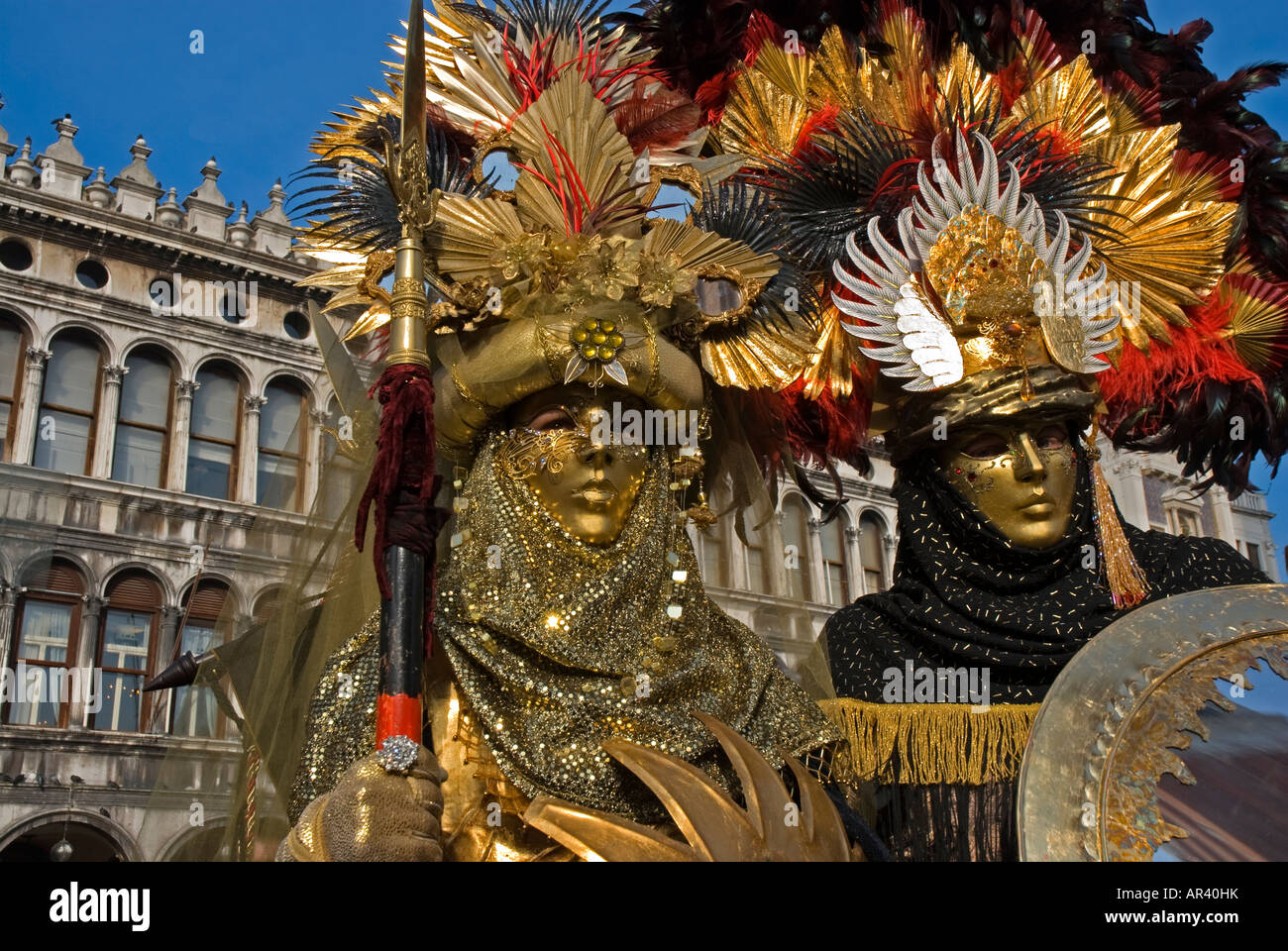 Two Carnival Venetian disguises of warrior with golden mask and spear Stock Photo