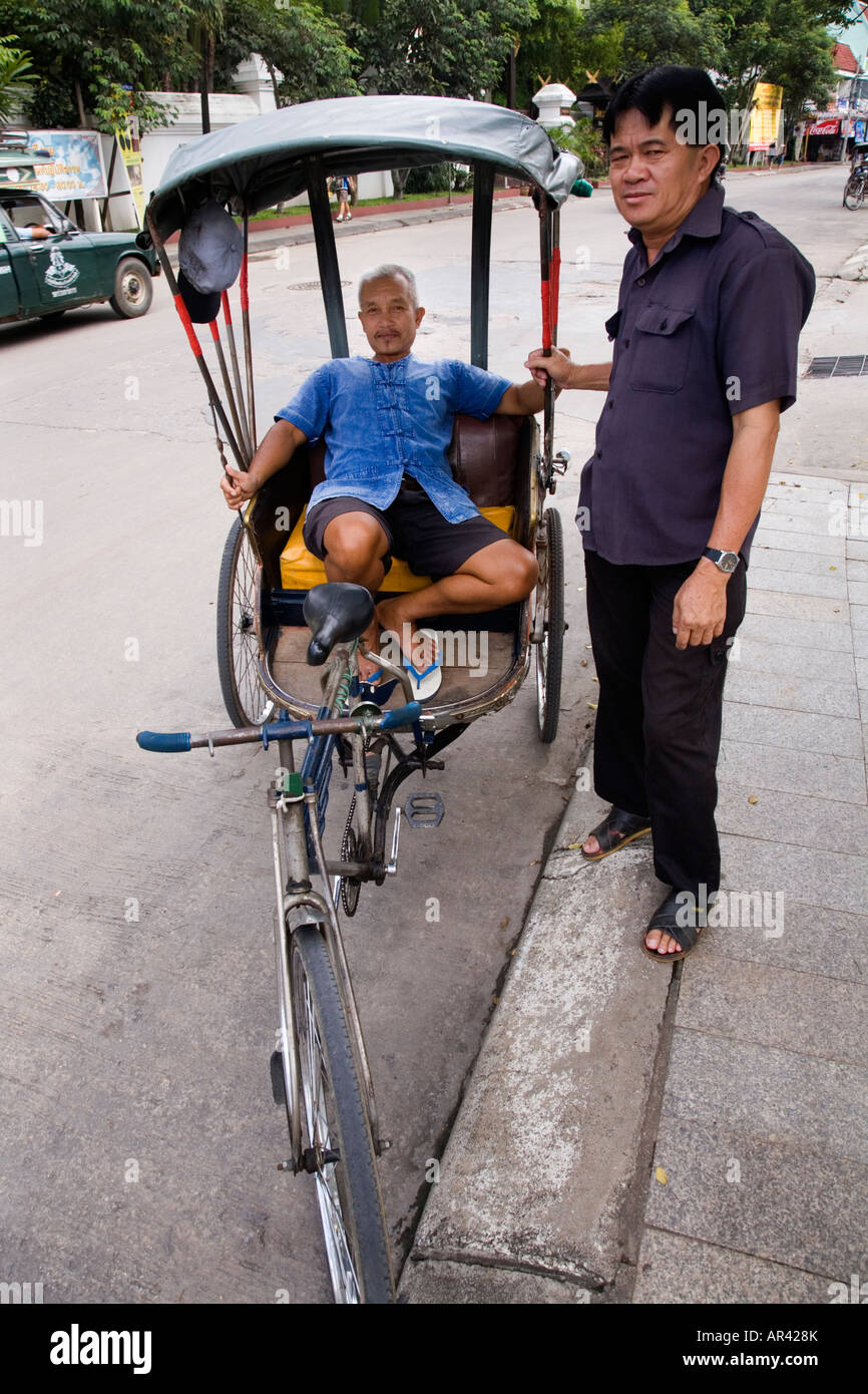The Rickshaw Rider Trishaw rider / rickshaw driver relaxing and talking to Thai pedestrian ...