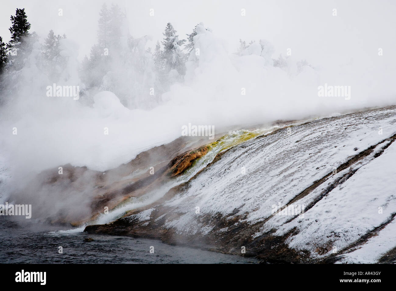 Yellowstone National Park in winter snow frost covered rock trees on Firehole River at Excelsior