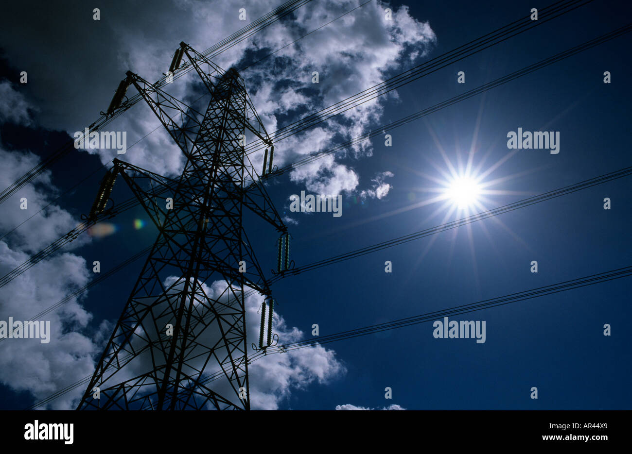 ELECTRICITY PYLON SET AGAINST A DARK CLOUDED SKY WITH SUN BEHIND Stock ...
