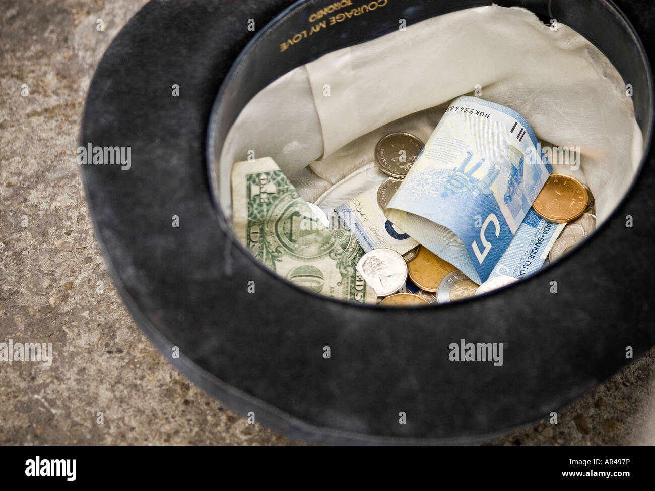 canadian-and-american-money-in-hat-collected-by-street-performer-AR497P.jpg
