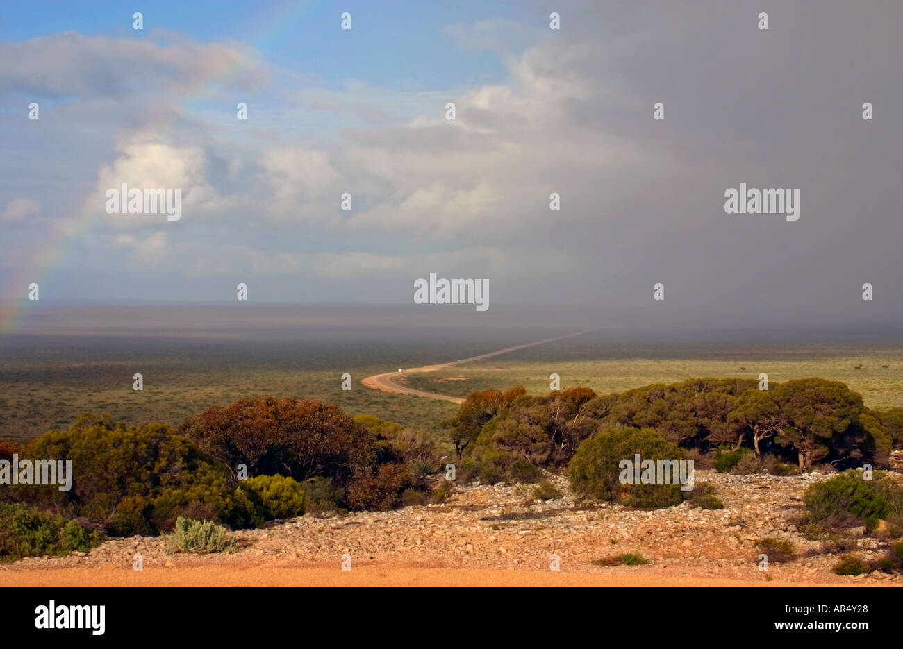 Rainbow arc over desert showers raining down on bush outside of Nullarbor National Park near Eucla Western Australia Stock Photo