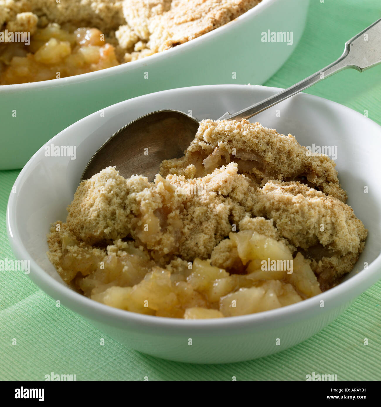 portion of apple crumble with dish in b/g Stock Photo