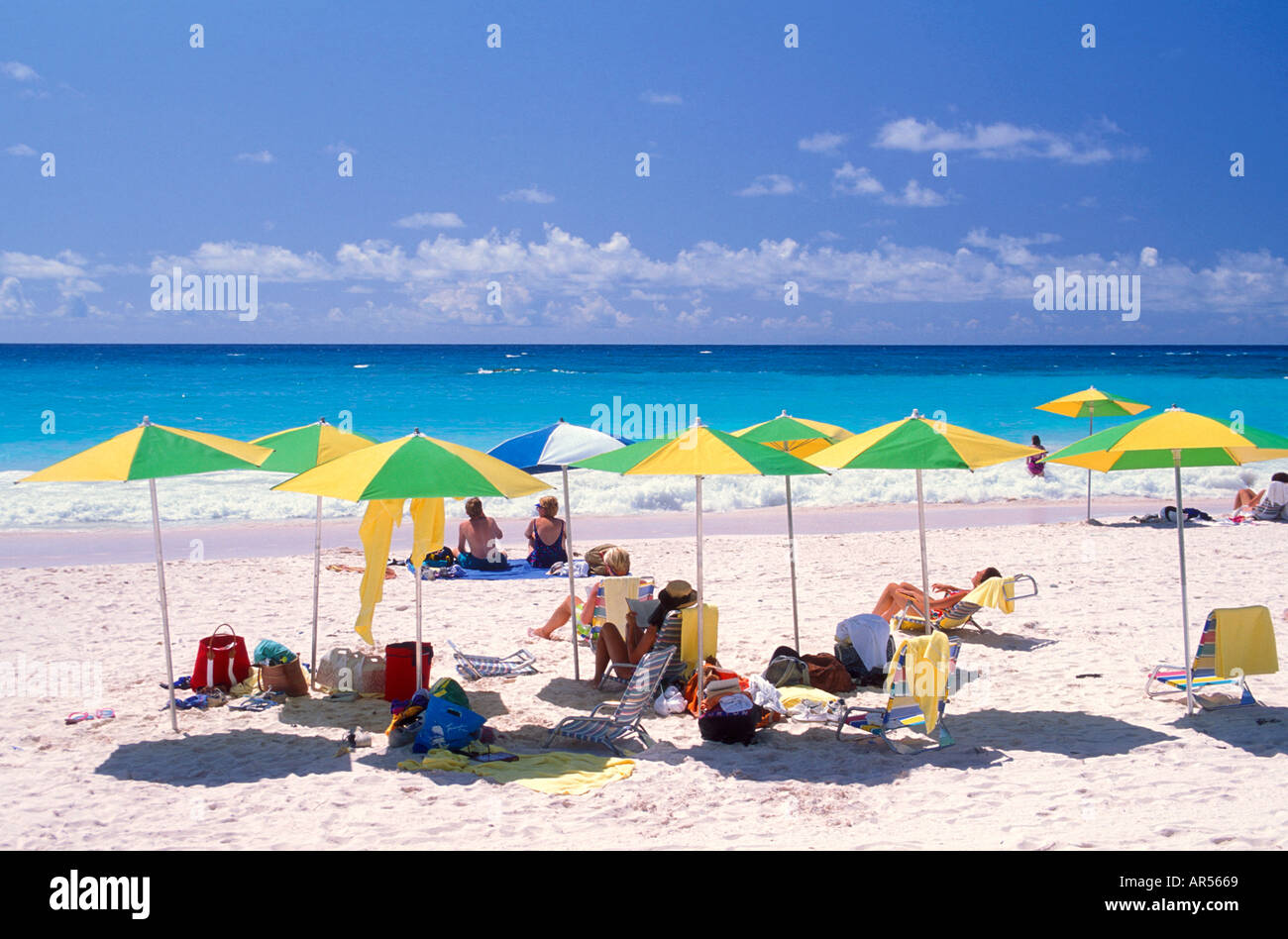 People sitting under colorful umbrellas at Horseshoe Bay Beach South Shore Park Bermuda Stock