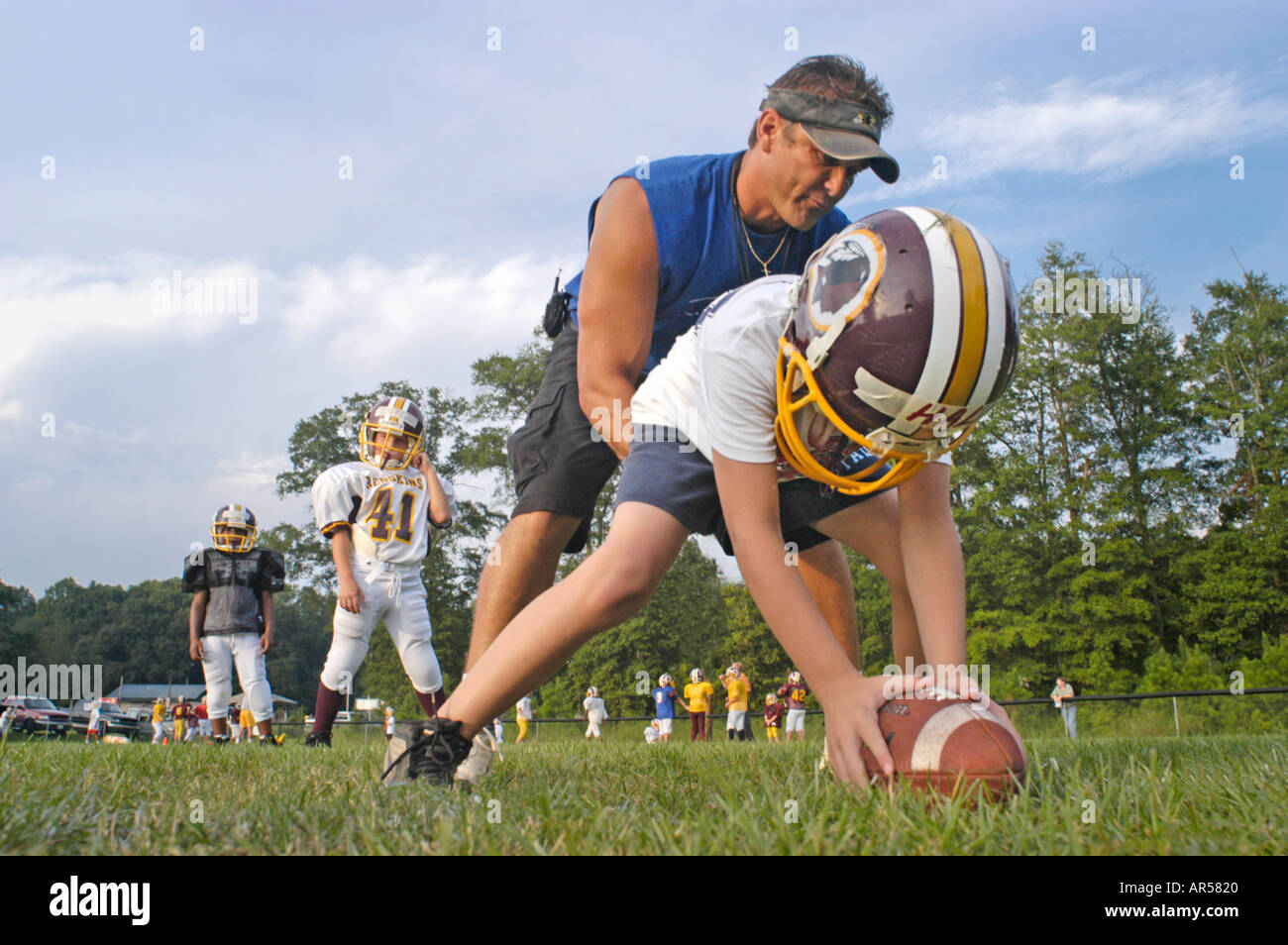 Football Coach teaching real kids how to play the game by being hands
