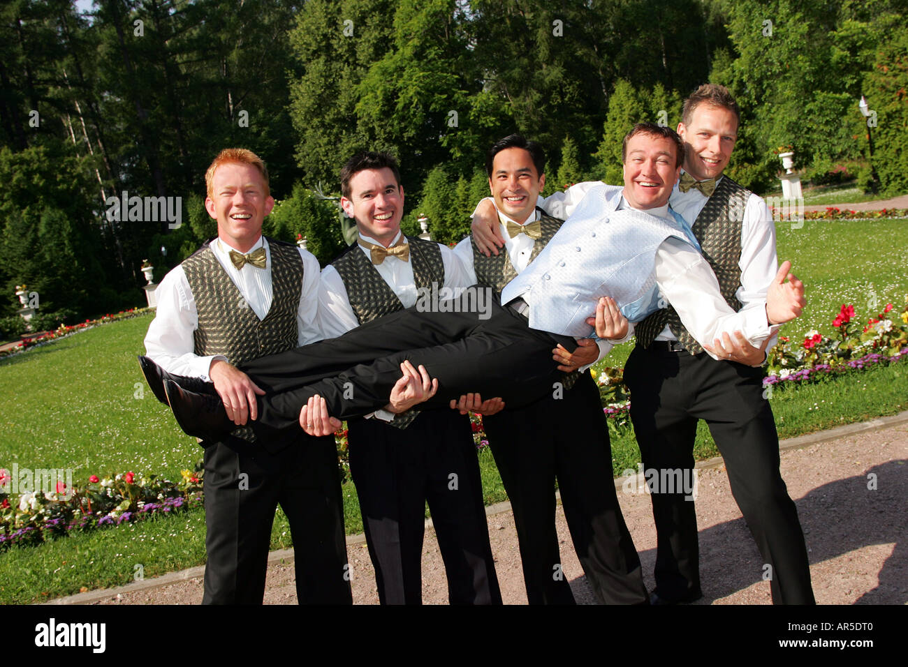 A Groom on his wedding day being held in the air by his groomsmen and best man Stock Photo