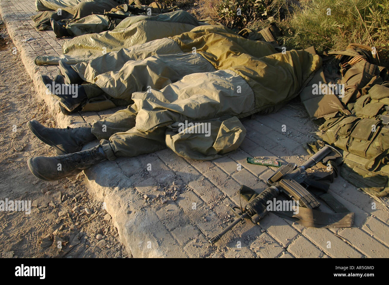 Israeli soldiers sleeping on a sidewalk in the town of Metula after returning from a night mission in southern Lebanon during Israel - Hezbullah war Stock Photo