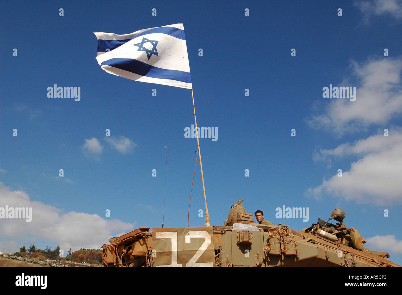 IDF soldier and Israeli flag  flapping in the wind on Merkava armoured tank, Israel Stock Photo