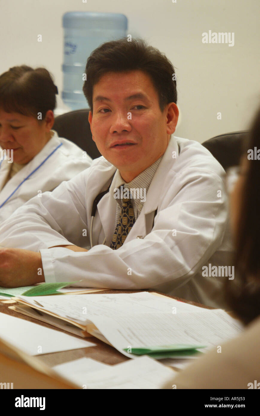 Doctor at Staff Meeting: Vietnamese-American community clinic, Garden Grove, California, USA. MODEL RELEASE Stock Photo