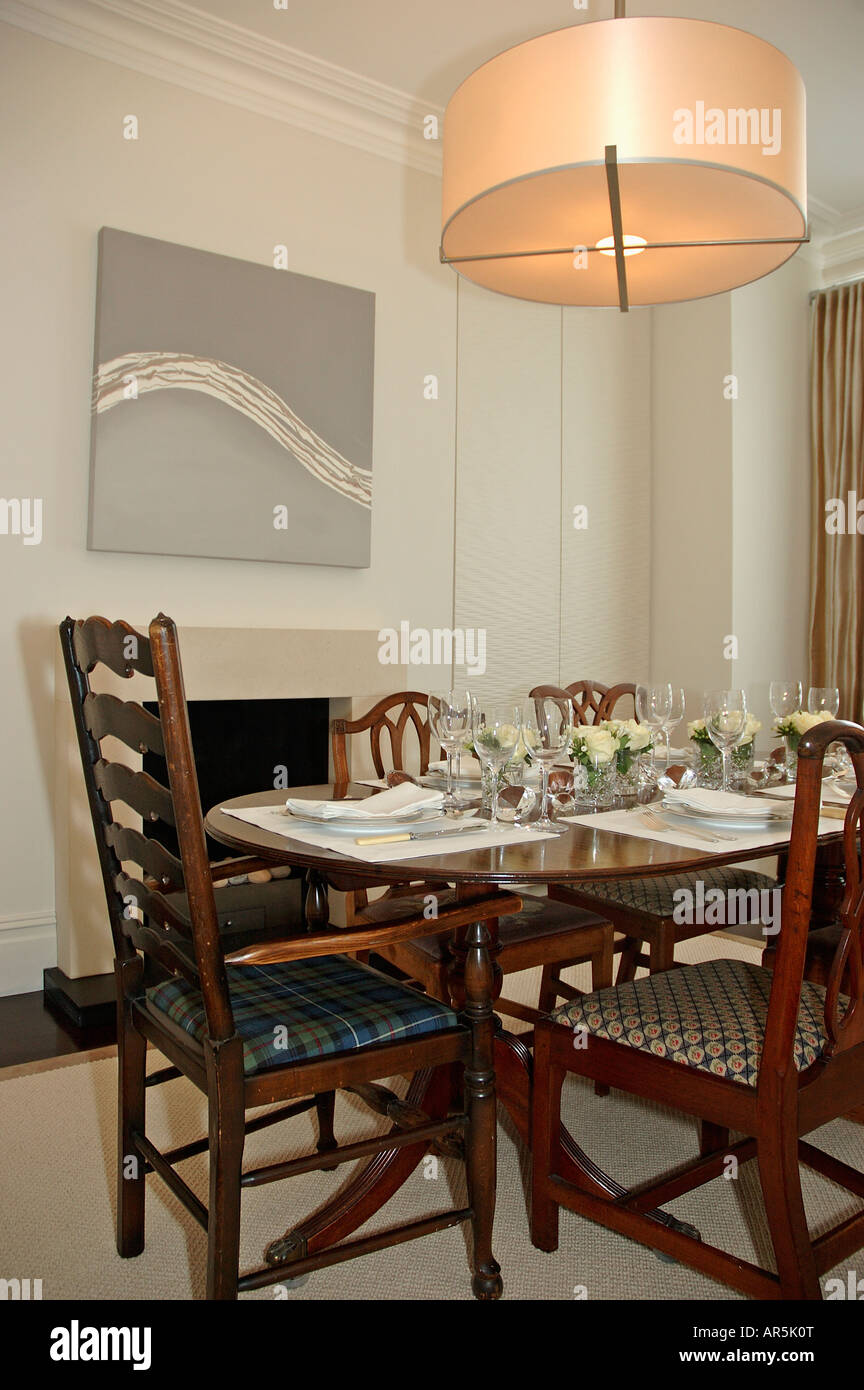 Modern circular light fitting above place settings on antique table