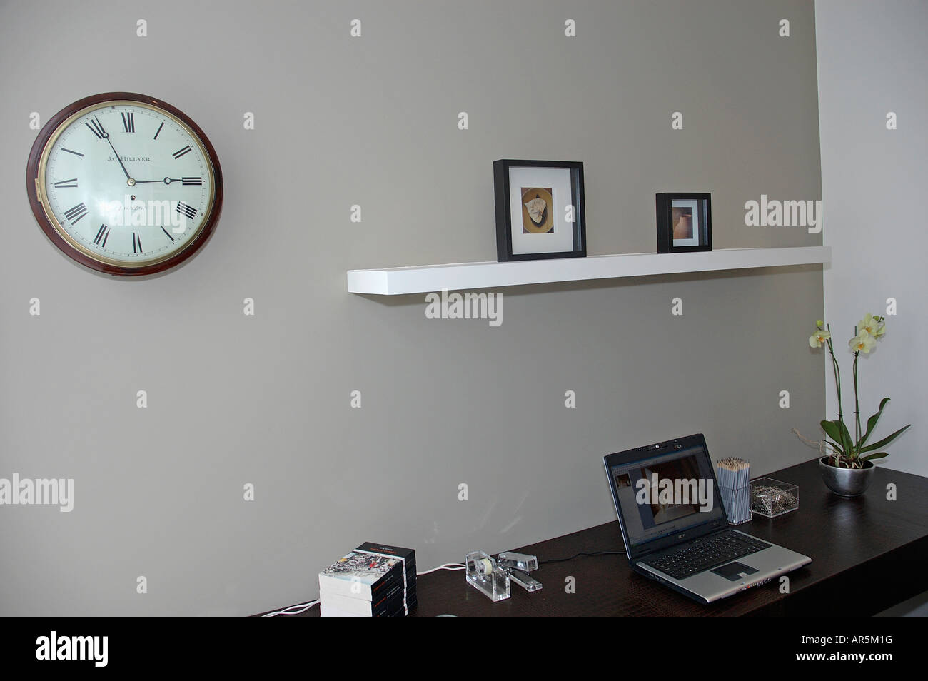 Circular Clock On Wall Above Laptop Computer On Desk In Modern