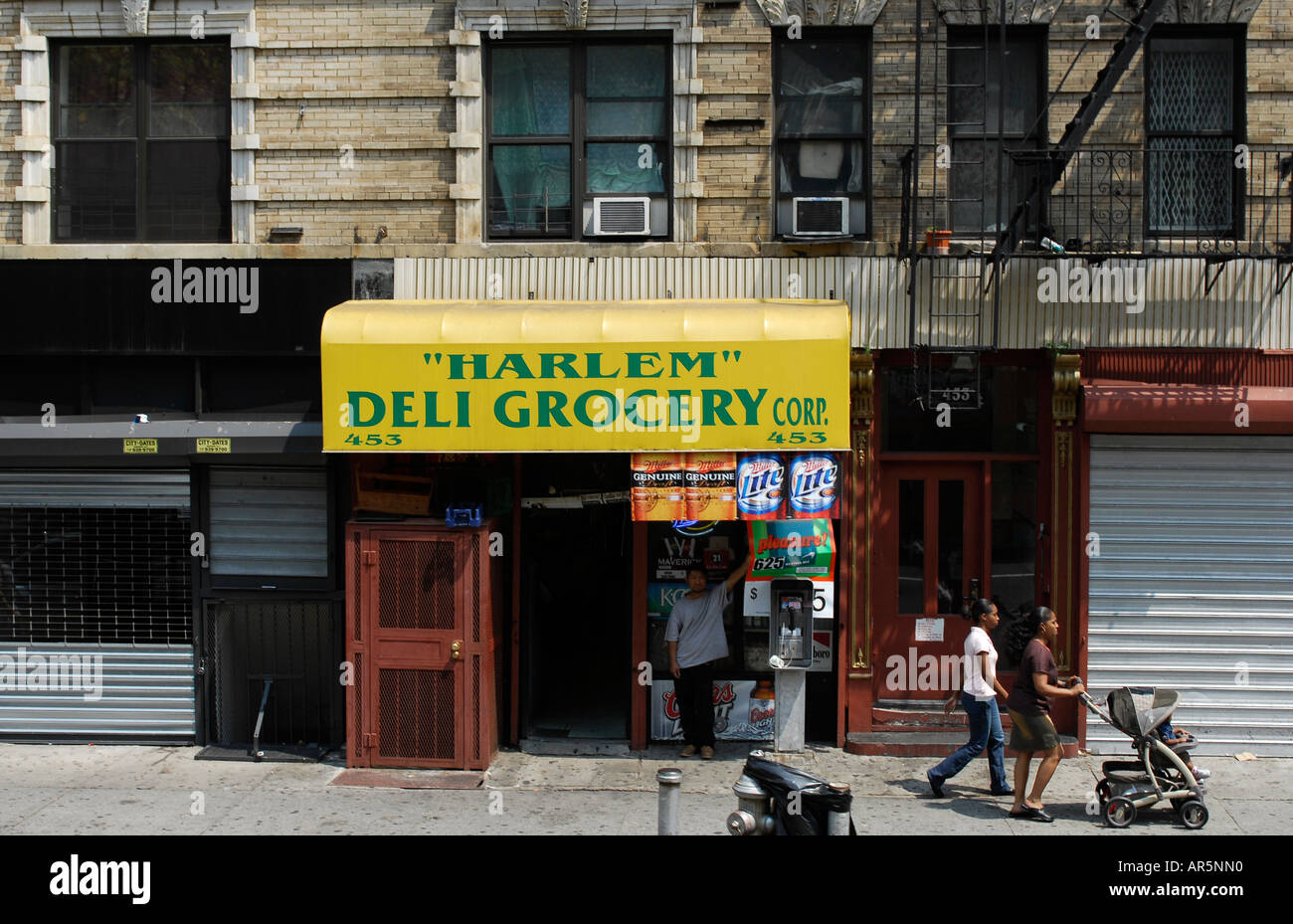 Two afro american girls with pushchair stroller walk past Harlem Deli Grocery Harlem New York Stock Photo