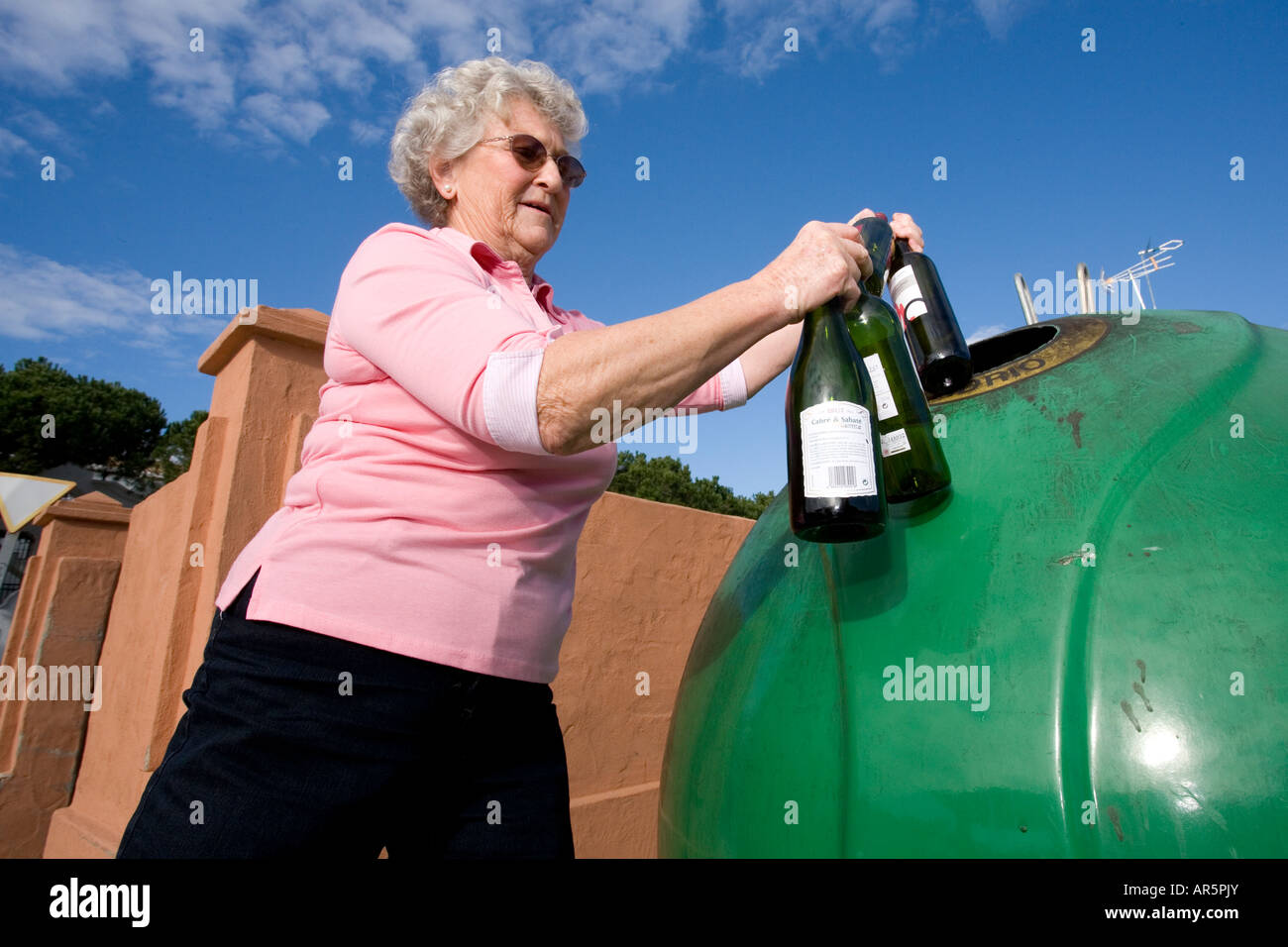 Senior woman throwing glass bottles into recycle bin Stock Photo Alamy