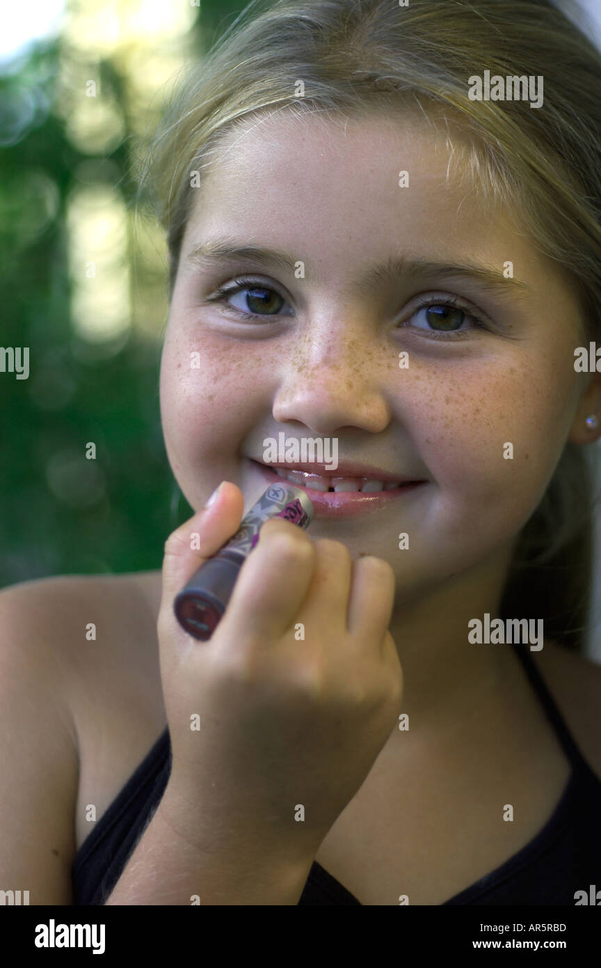 young girl putting on lip gloss Stock Photo