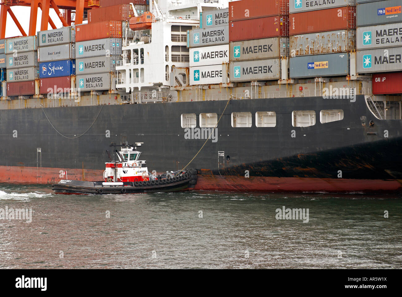 Tugboat assisting a container ship onto a berth in the container port, Vancouver harbour. Stock Photo