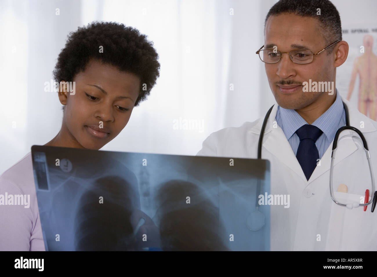 African male doctor and patient looking at x-ray Stock Photo