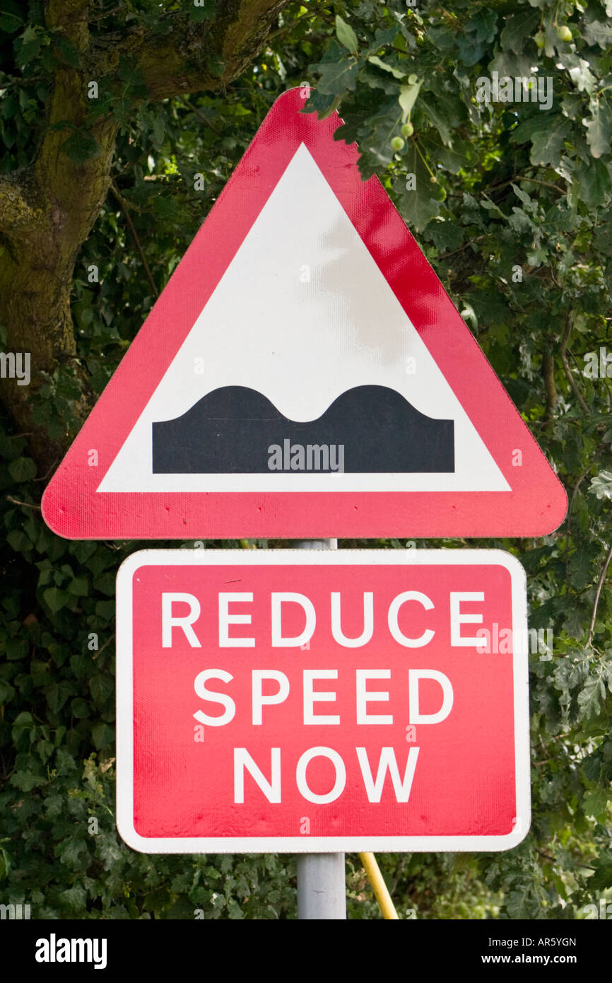 Caution reduce speed now bumps in road road sign Stock Photo