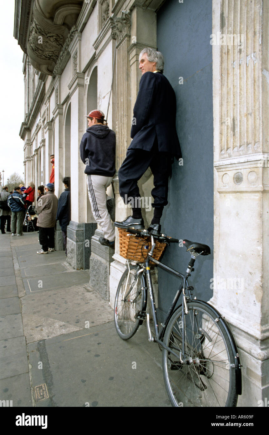 Businessman standing on bicycle handlebars watching Queen Mother s funeral procession Stock Photo