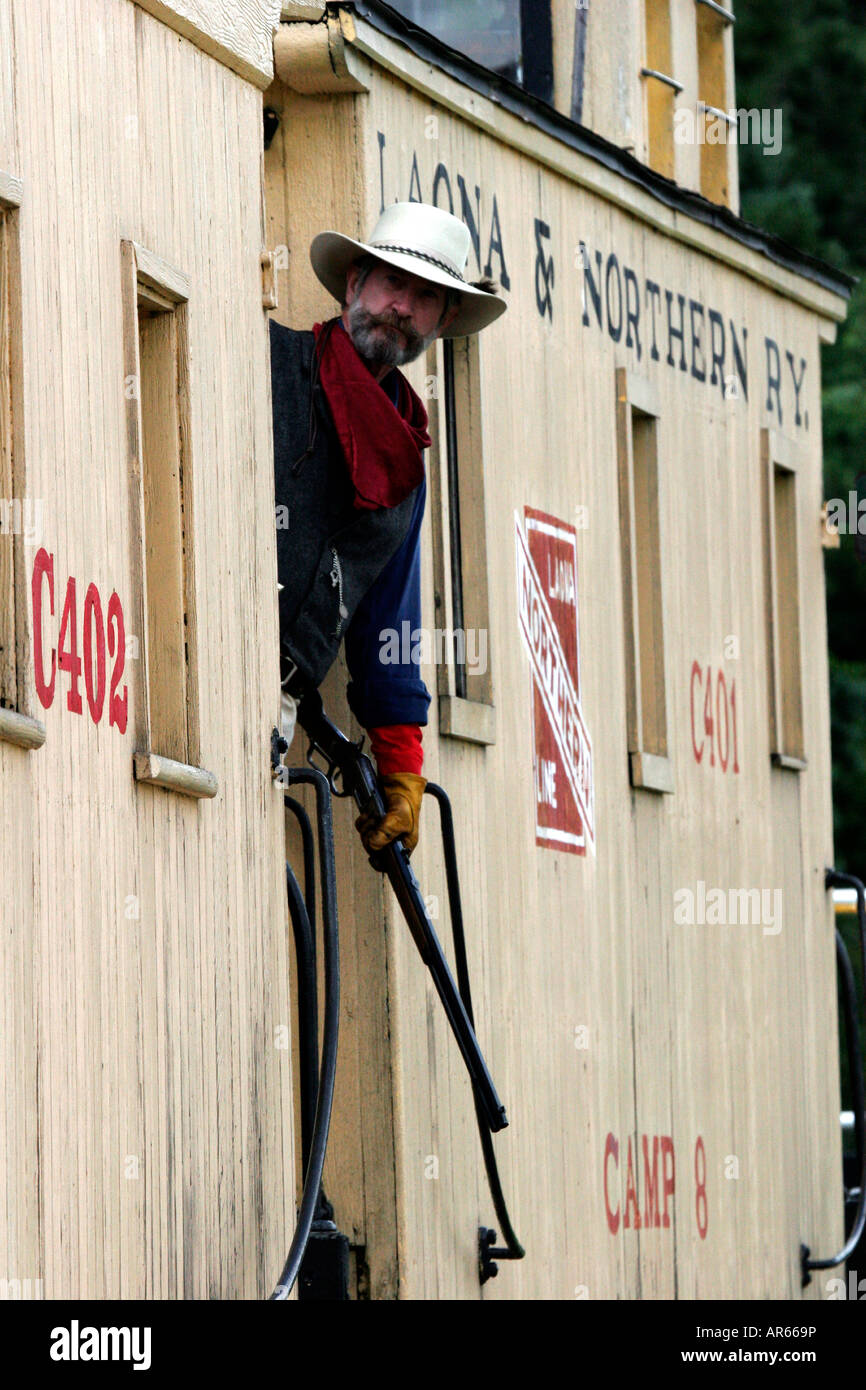 A cowboy with a rifle riding the caboose at the end of a steam engine at a western reenactment in Wisconsin Stock Photo