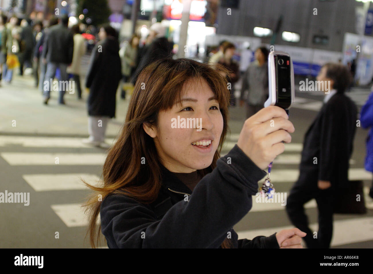 Young woman with cellular phone, mobil phone, at night, pedestrian crossing, East Shinjuku, Tokyo, Japan Stock Photo