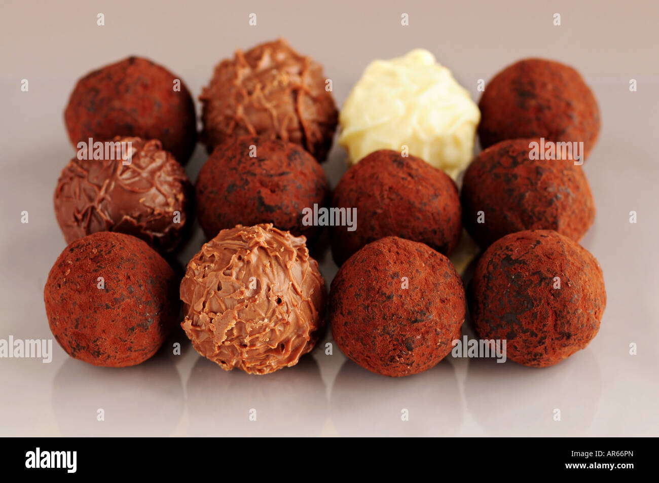 Several assorted chocolate truffles in rows on brown background Stock Photo