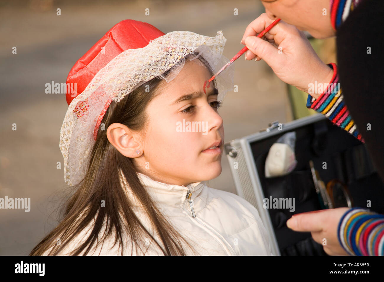 Girl having her face painted at the Carnival in Venice, Italy Stock Photo