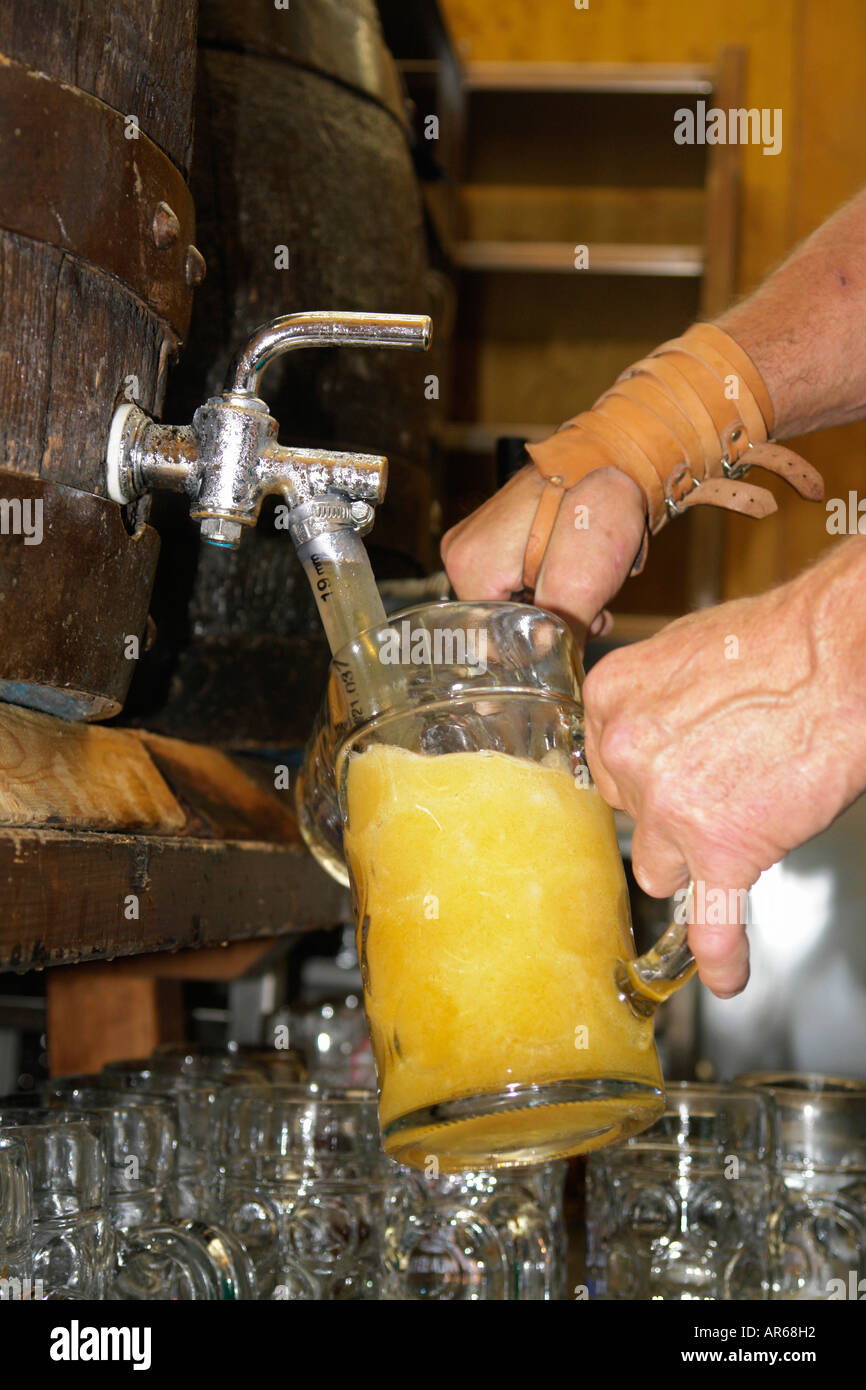 Bar tender at Munich Beer Festival Oktoberfest  busy pouring liter beer from Barrel to glasses. Stock Photo