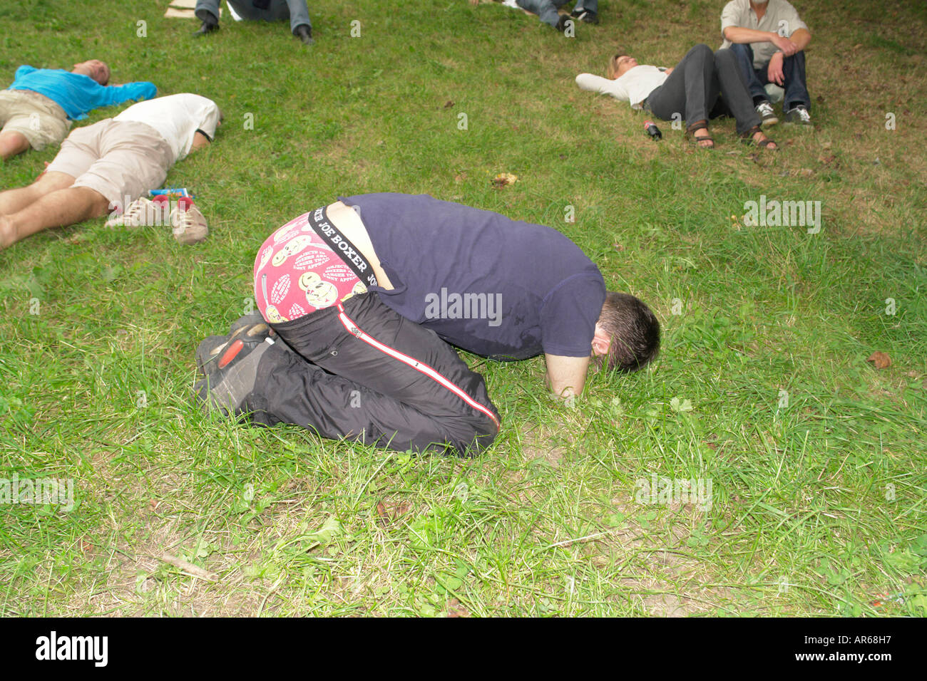 Drunken man lying on grassland unconscious Oktoberfest in Theresienwiese Munich Bavaria Germany Stock Photo