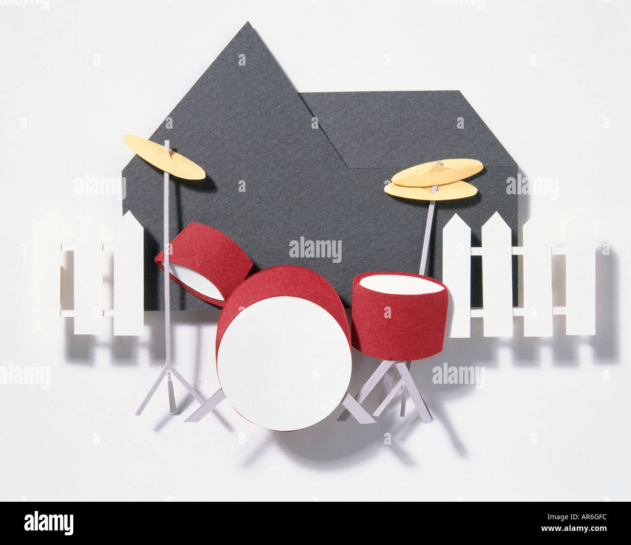 Paper model of a drum kit, red drums with gold symbol, outside black  silhouetted of house and white picket fence Stock Photo - Alamy