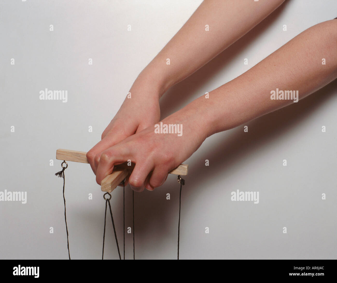 Child's hands holding the wooden cross of string puppet, controlling