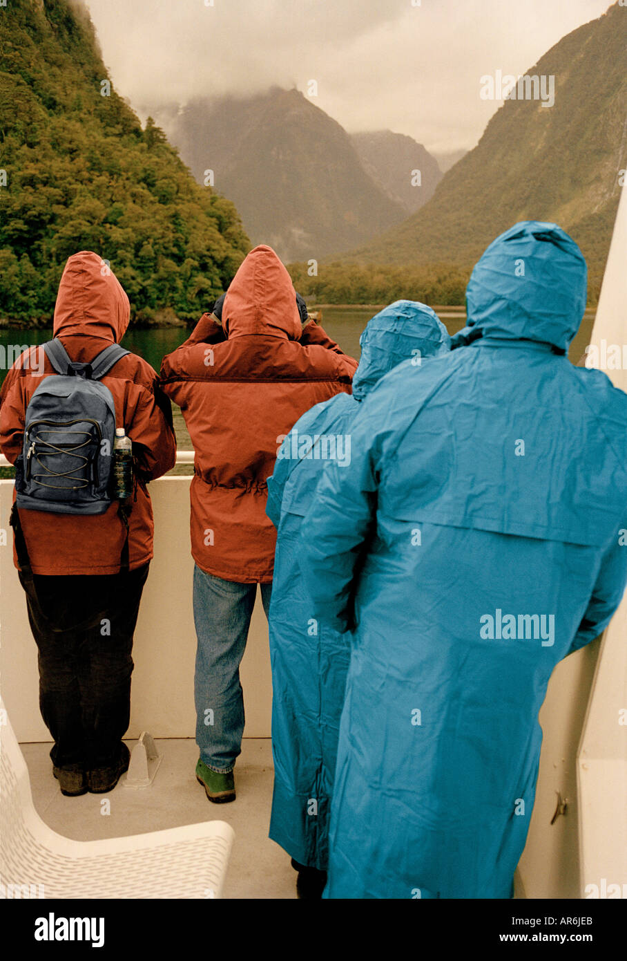 Two couples wearing waterproof coats on boat in Milford Sound New Zealand Stock Photo