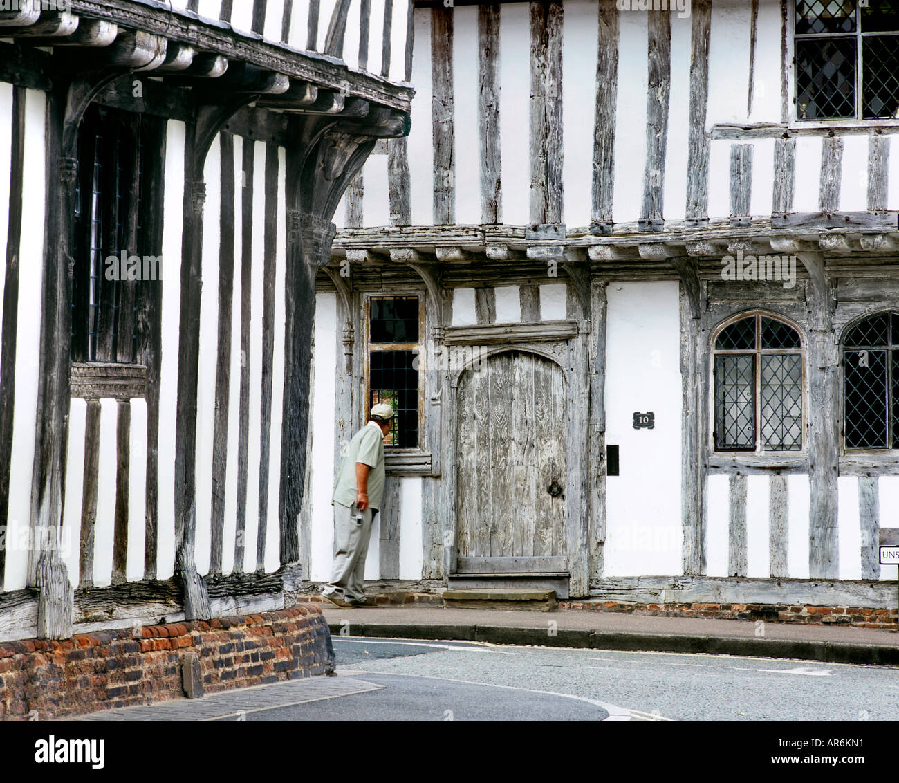 Nosy tourist peeking into old half timbered buildings in School Lane, Lavenham, Suffolk. Stock Photo