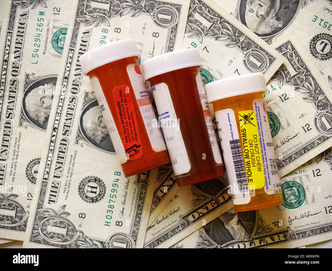 Prescription pill bottles against a background of dollar bills. Stock Photo