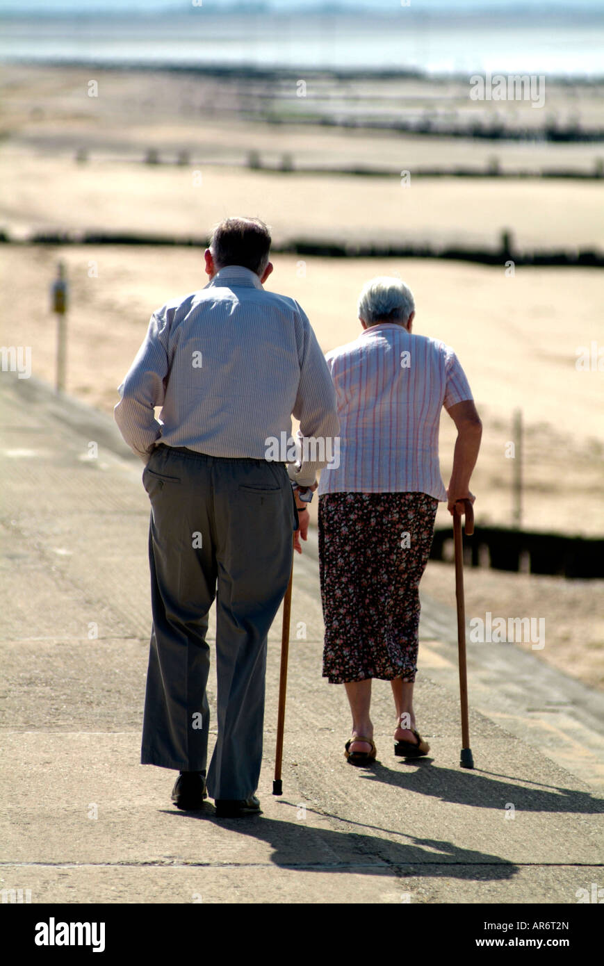 senior citizens walking together with sticks along seawall at Hunstanton Norfolk UK Stock Photo