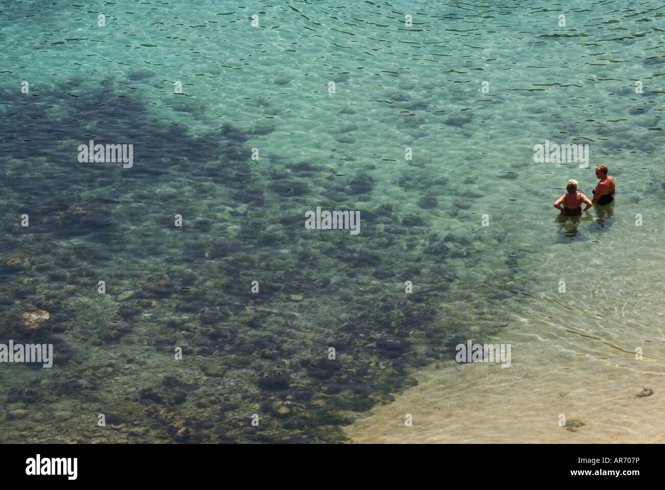 Mature Holidaymakers standing in the crystal clear Mediterranean sea in Greece Stock Photo